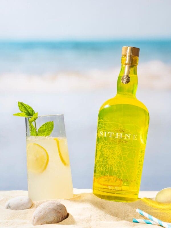 Sithney A Bottle Of Lemon Gin On A Beach Next To Glass