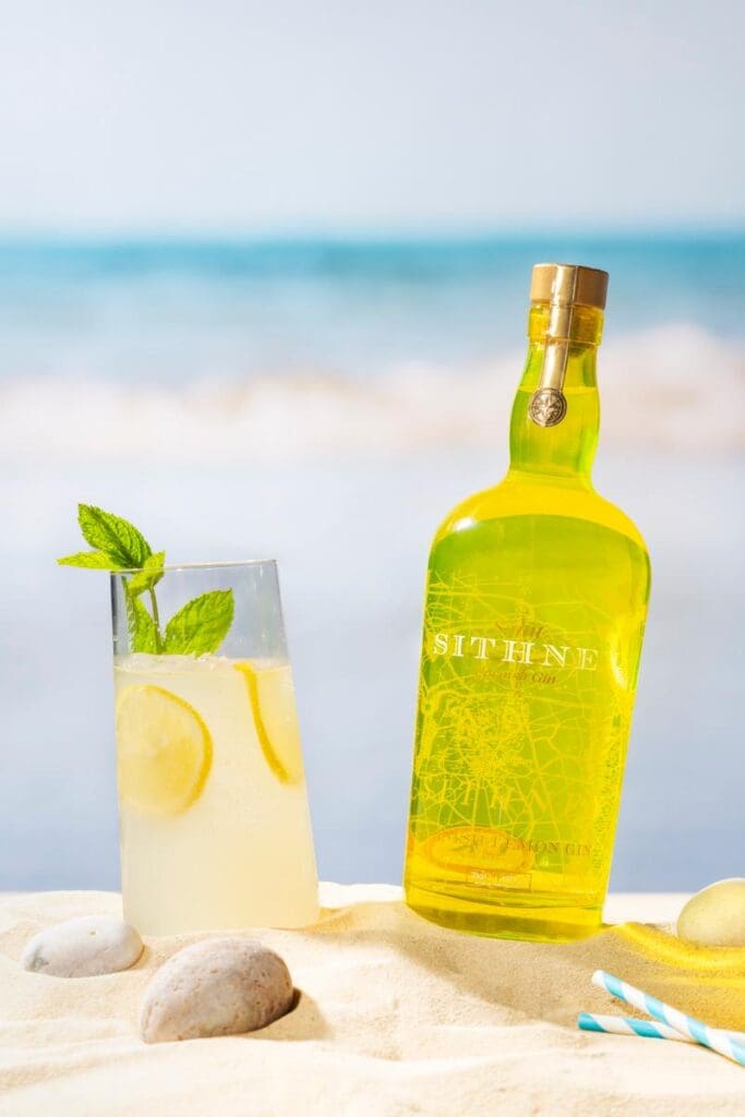 Sithney A Bottle Of Lemon Gin On A Beach Next To Glass